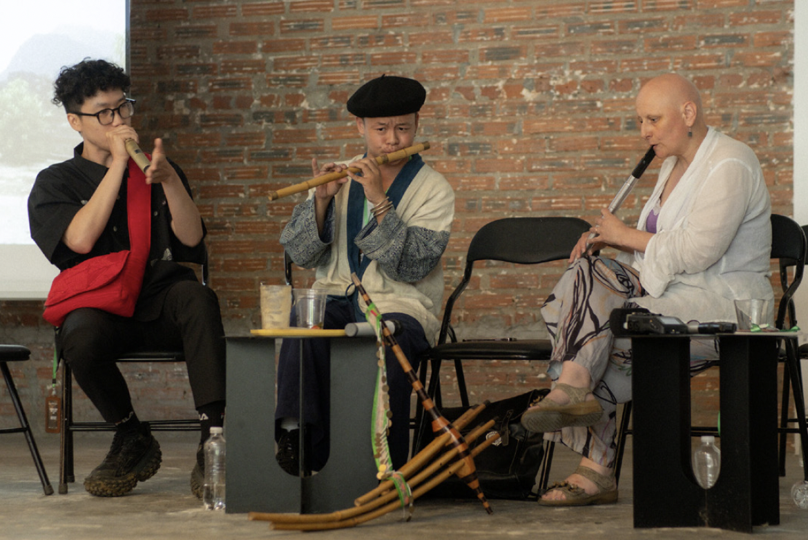 Three musicians sitting down playing musical instruments