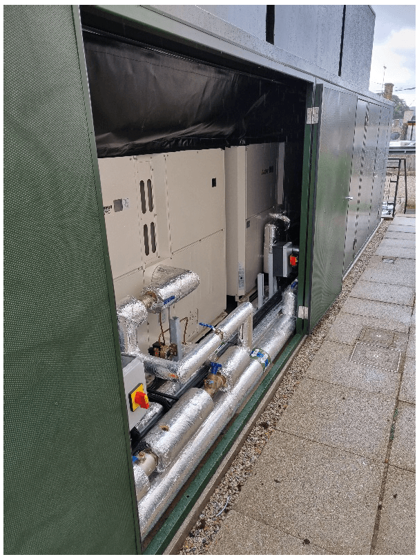 Three air source heat pumps within a green soundproof enclosure.