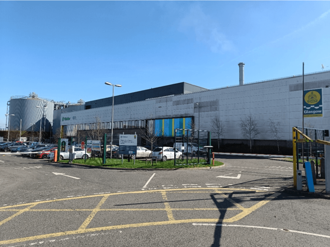 A parking lot with cars parked in front of the Glasgow Recycling building.