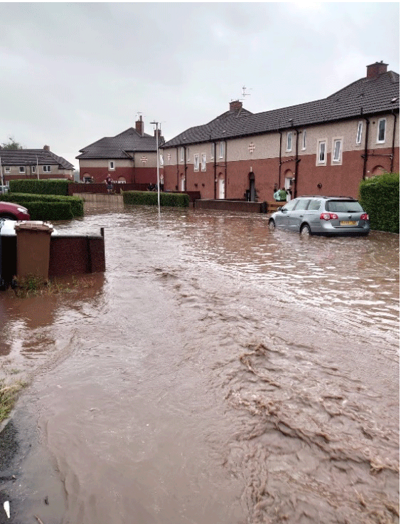 A flooded street in Tillicoultry in 2020 showing with cars and houses.