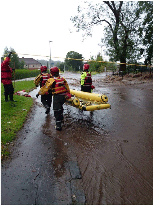 A group of people carrying a raft during a flood event in Tillicoultry