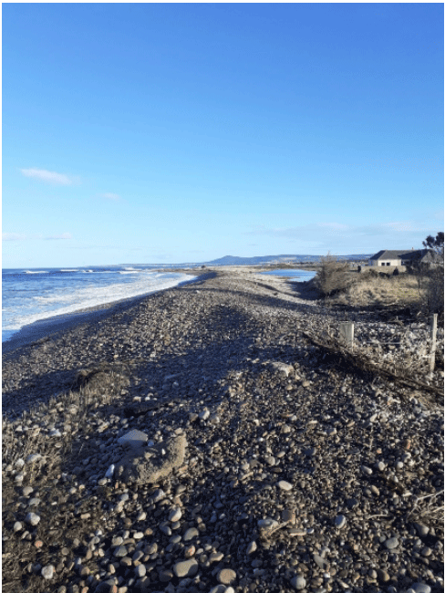 The Moray Coastline - a rocky beach with a body of water and a house.