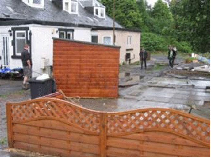 A group of people standing outside a house that has been flooded