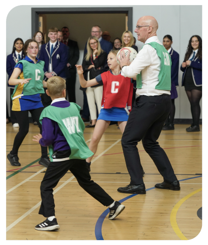 The First Minister, John Swinney, playing netball with young people