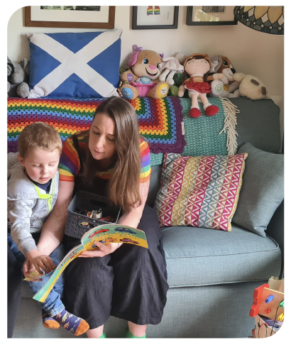 A person reading a story to a young child and sitting on a sofa