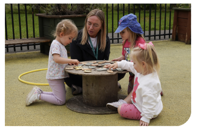 Case study: A childcare working sitting on the ground outside playing with 3 young children